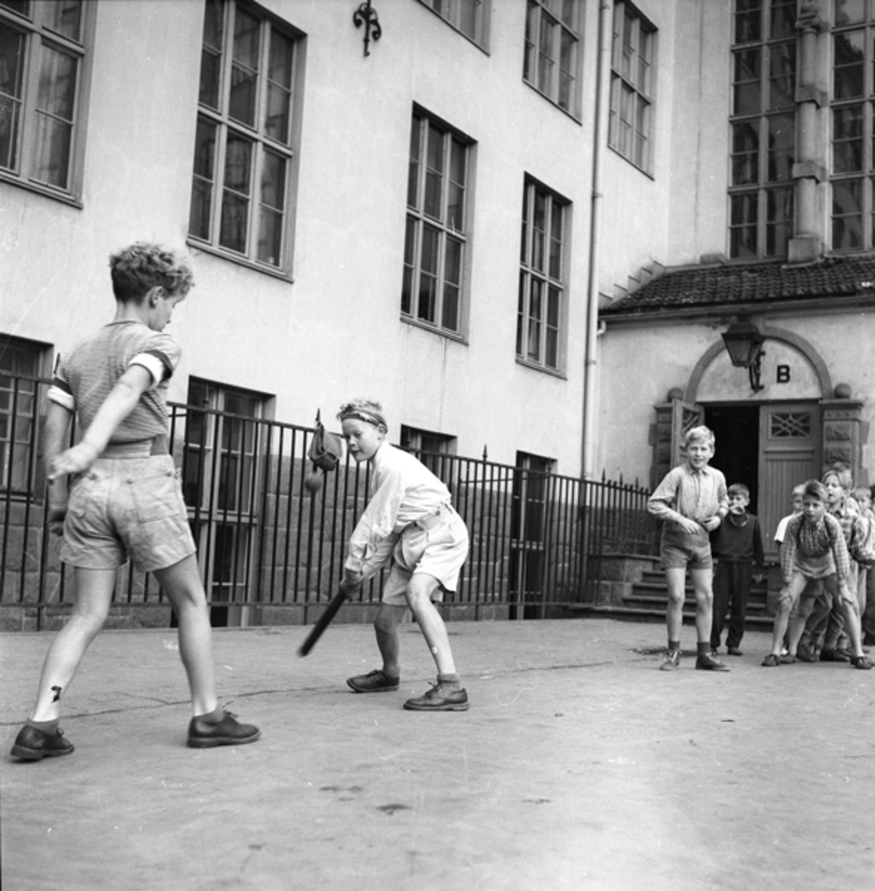 11 Foto: Ukjent/ Osloibilder.no/Arbark. Bildetekst: Gutter slår ball i skolegården på Hersleb Skole,.1952