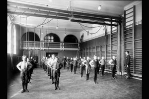 15 Fotograf ukjent, 1922. Byarkitekten. Bildenummer: A-20031/Ua/0003/012. Utlånt av Oslo byarkiv. Bildetekst: Gymsal, gymnastikk, linjegymnastikk, gymtime, ribbevegg, bommer. Og legg merke til antrekket! Herslebs skole 1922