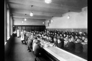16 Fotograf ukjent, 1922. Byarkitekten. Bildenummer: A-20031/Ua/0003/016. Utlånt av Oslo byarkiv. Bildetekst: Gymsal, gymnastikk, linjegymnastikk, gymtime, ribbevegg, bommer. Og legg merke til antrekket! Herslebs skole 1922