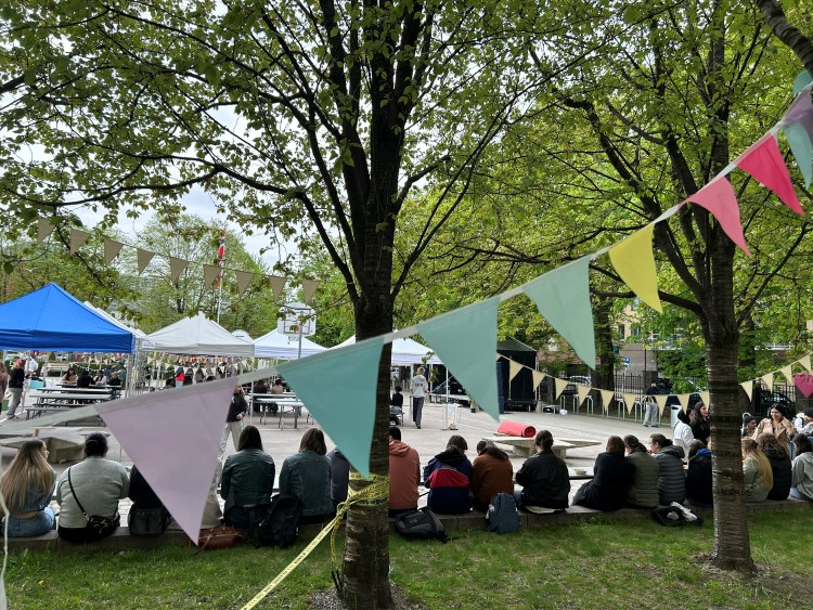 en gruppe mennesker som sitter i et gressområde med telt og trær